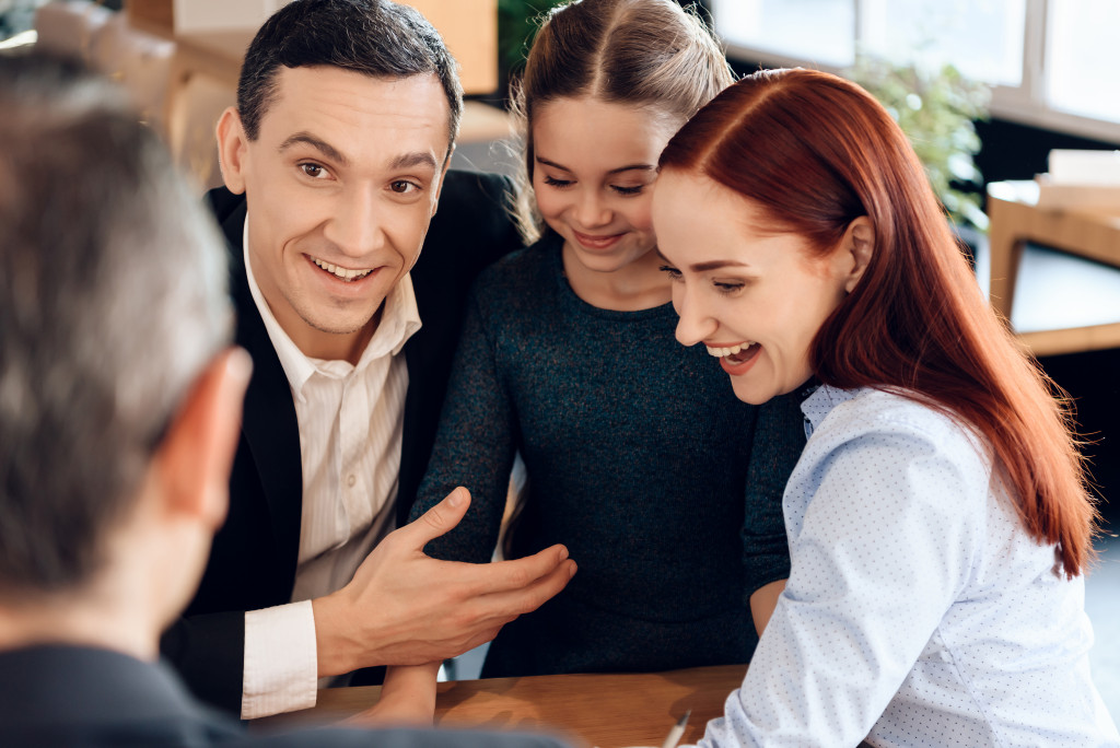 Divorcing couple communicating with each other while their daughter stands between them.